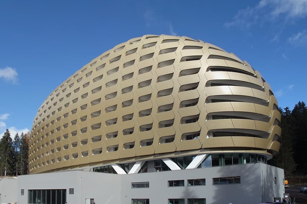 The curved golden shell of the AlpenGold Hotel against a blue sky